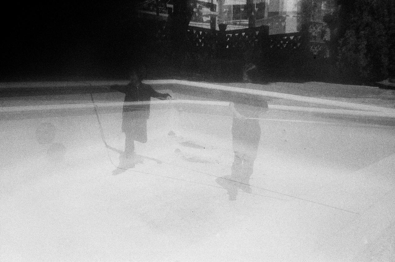 A double exposure in black and white: two figures standing in an empty swimming pool, their outlines overlapping
